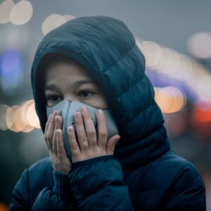 a person covering their face in a mask outside